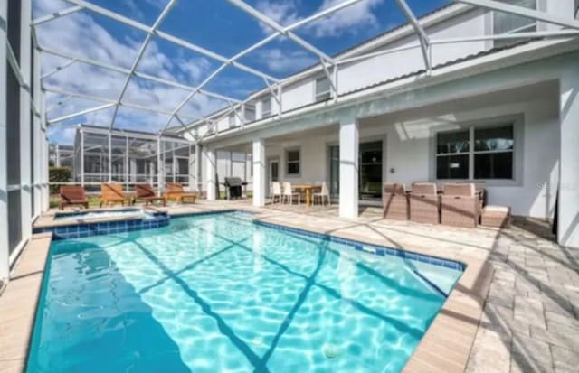 view of pool featuring a lanai, an in ground hot tub, and a patio area