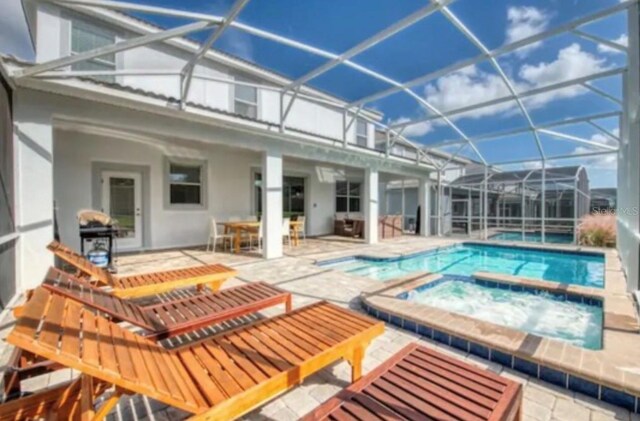 view of pool featuring a lanai, a patio, and an in ground hot tub