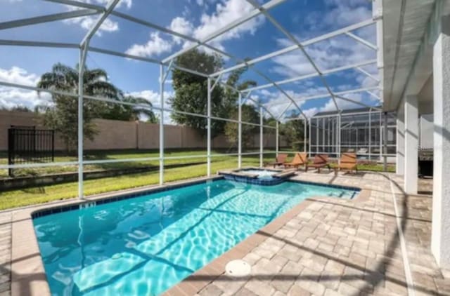 view of pool featuring glass enclosure, a lawn, and a patio