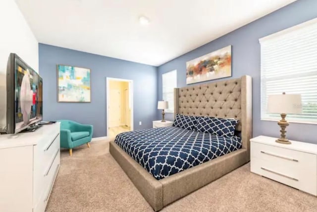 bedroom with multiple windows, ensuite bathroom, and light carpet