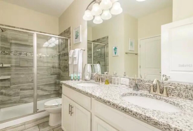 bathroom featuring tile patterned flooring, vanity, toilet, and a shower with shower door