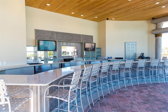 kitchen featuring a high ceiling, wood ceiling, and stone countertops