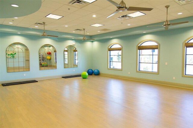 workout area featuring a paneled ceiling, ceiling fan, and light hardwood / wood-style floors