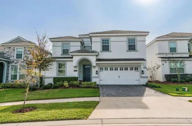 view of front of house featuring a tiled roof, a front lawn, decorative driveway, and an attached garage