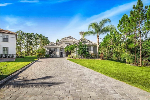 mediterranean / spanish house with stucco siding, decorative driveway, and a front yard