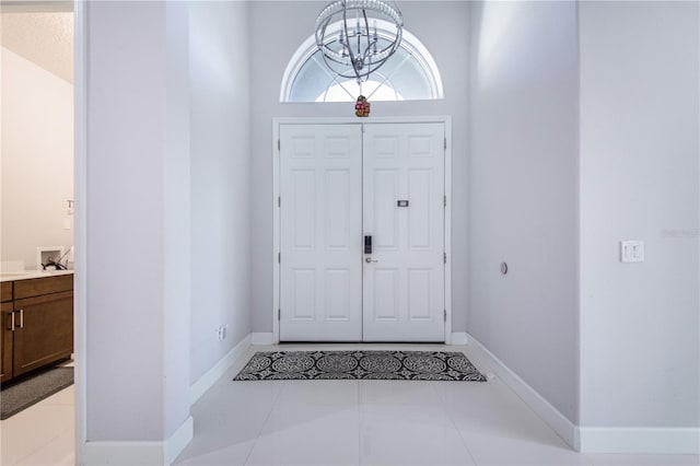 entrance foyer with a towering ceiling, a notable chandelier, and light tile patterned flooring