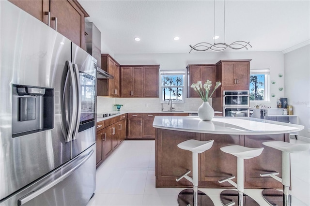 kitchen with pendant lighting, appliances with stainless steel finishes, a kitchen bar, a center island, and sink