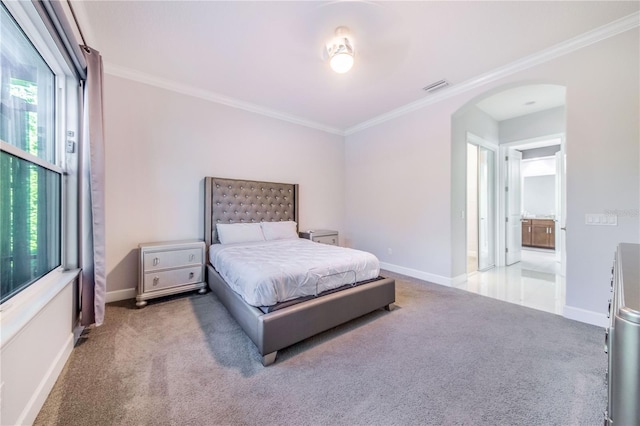 carpeted bedroom featuring ornamental molding and ensuite bath