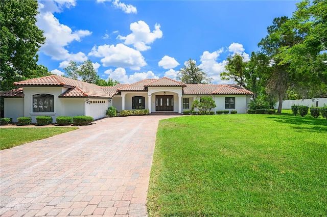 mediterranean / spanish home featuring a garage and a front lawn