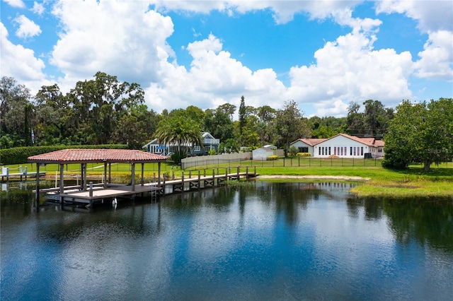 view of dock with boat lift, a lawn, a water view, and fence