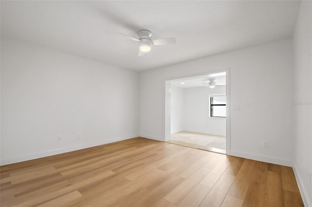 unfurnished room featuring light wood-type flooring, a ceiling fan, and baseboards