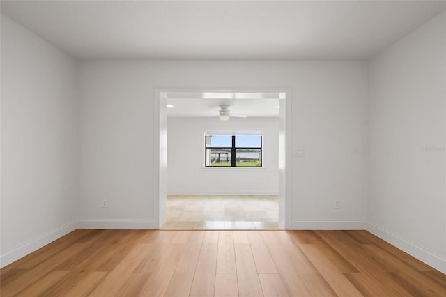 empty room featuring light wood-style floors, ceiling fan, and baseboards