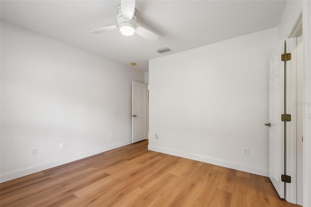 spare room featuring light wood-style flooring, visible vents, baseboards, and a ceiling fan