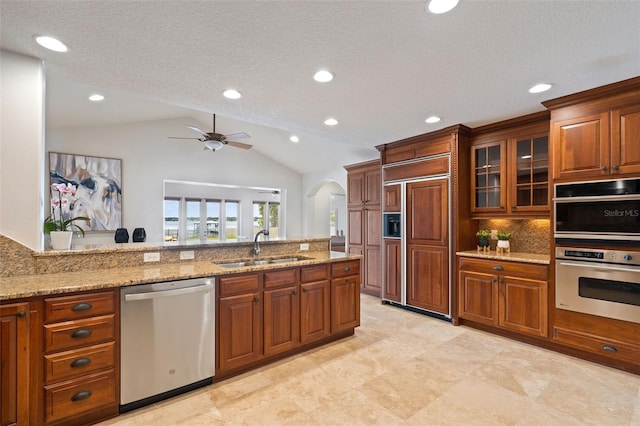 kitchen with vaulted ceiling, appliances with stainless steel finishes, sink, ceiling fan, and a textured ceiling