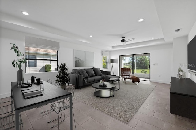 tiled living room featuring a tray ceiling and ceiling fan