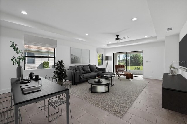 living room featuring a tray ceiling, recessed lighting, visible vents, and baseboards