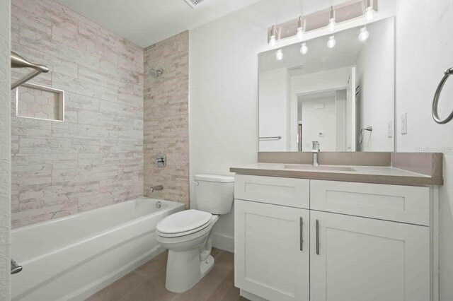 full bathroom featuring tiled shower / bath, vanity, and toilet