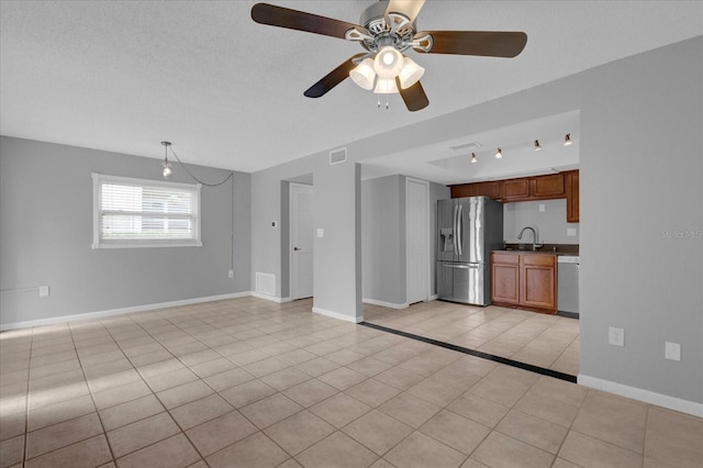 unfurnished living room featuring a textured ceiling, light tile patterned flooring, a sink, visible vents, and baseboards