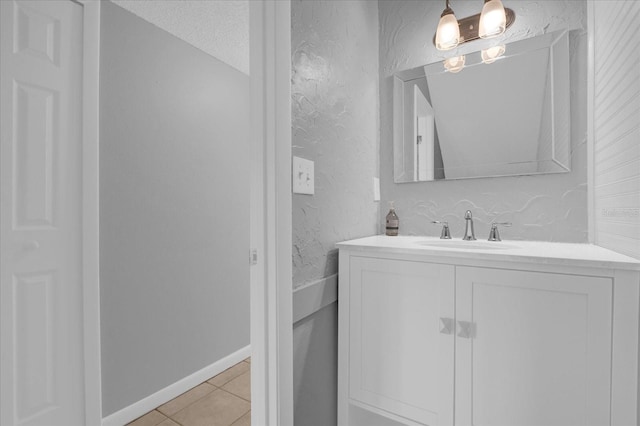 bathroom with a textured wall, tile patterned flooring, and vanity