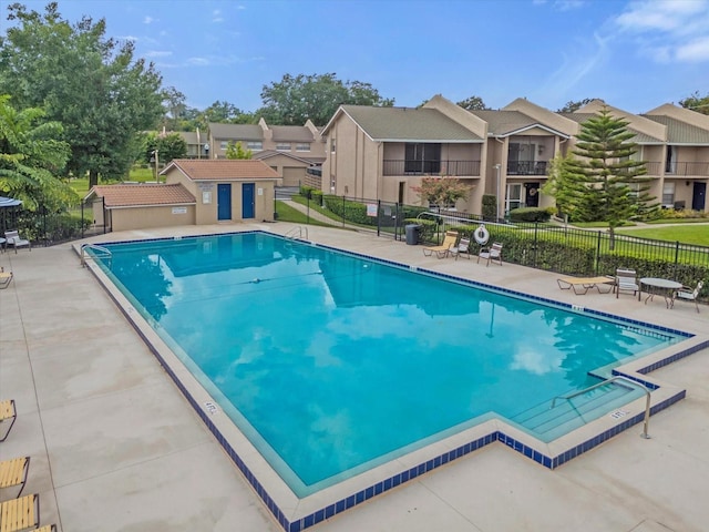 pool with a patio area, a residential view, and fence