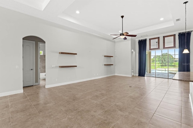 unfurnished living room featuring ceiling fan, light tile patterned floors, crown molding, and a tray ceiling