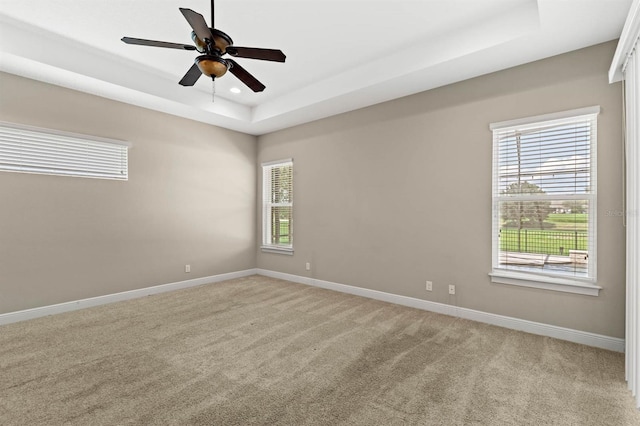 unfurnished room featuring a raised ceiling, light colored carpet, and ceiling fan