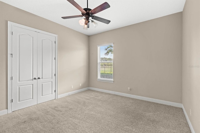 unfurnished bedroom featuring ceiling fan, light colored carpet, and a closet