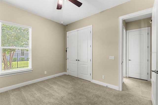 unfurnished bedroom featuring ceiling fan, a closet, and light carpet