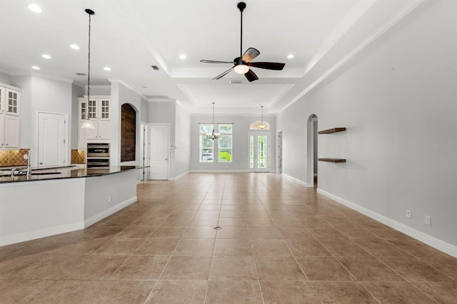 unfurnished living room featuring ceiling fan, a tray ceiling, crown molding, light tile patterned flooring, and sink