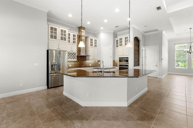 kitchen with stainless steel appliances, wall chimney range hood, pendant lighting, and a spacious island