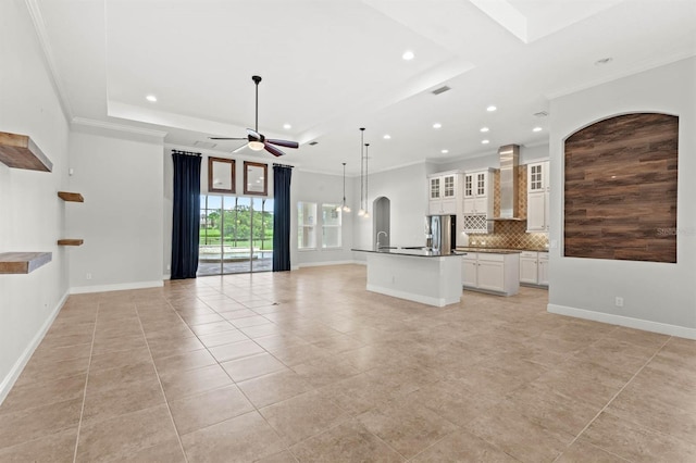 unfurnished living room with crown molding, light tile patterned floors, ceiling fan, and a tray ceiling