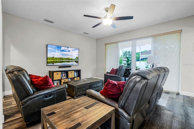 living room featuring ceiling fan, dark wood-type flooring, and a textured ceiling