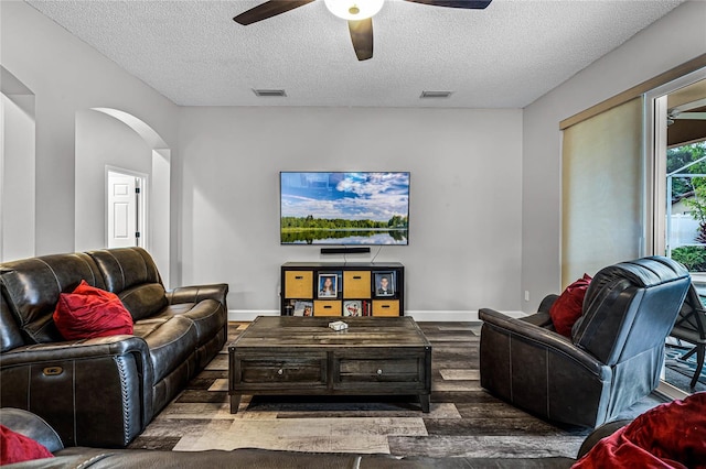 living room with ceiling fan, a textured ceiling, and dark hardwood / wood-style flooring