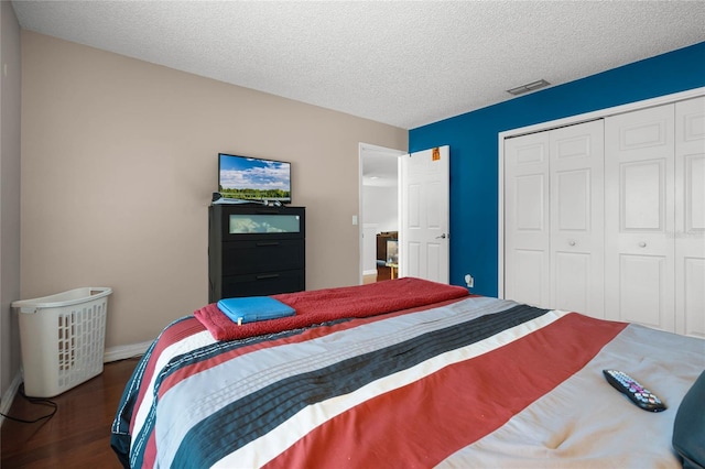 bedroom featuring a textured ceiling, a closet, and dark hardwood / wood-style flooring