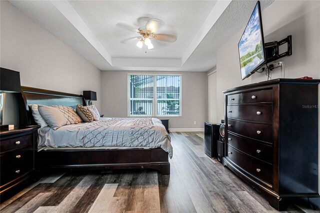 bedroom featuring hardwood / wood-style flooring, a tray ceiling, and ceiling fan