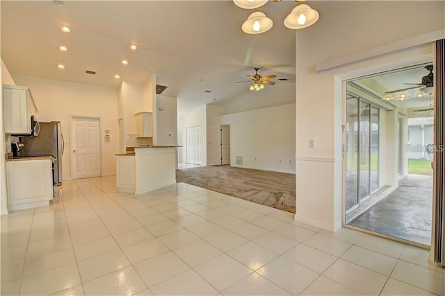 interior space with ceiling fan, light tile patterned floors, vaulted ceiling, and light colored carpet