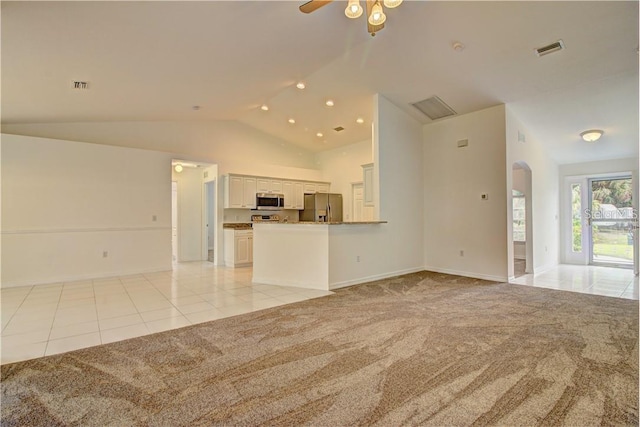 unfurnished living room featuring arched walkways, light colored carpet, visible vents, and light tile patterned floors