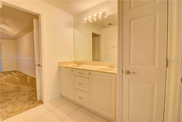 bathroom with baseboards, double vanity, a sink, and tile patterned floors