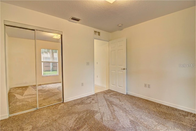 unfurnished bedroom featuring baseboards, a textured ceiling, visible vents, and carpet flooring