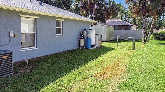 view of yard with central AC, an outdoor structure, a storage shed, and fence