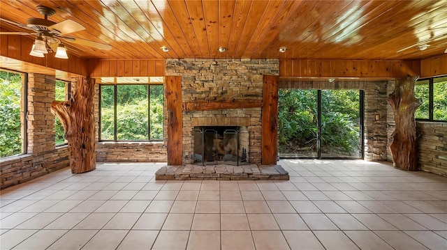 unfurnished living room with a stone fireplace, wooden ceiling, and tile patterned floors