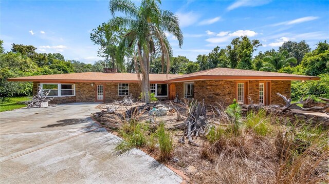 ranch-style home with driveway and a chimney