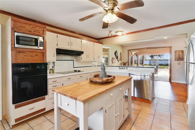 kitchen with under cabinet range hood, a peninsula, ornamental molding, decorative backsplash, and black appliances