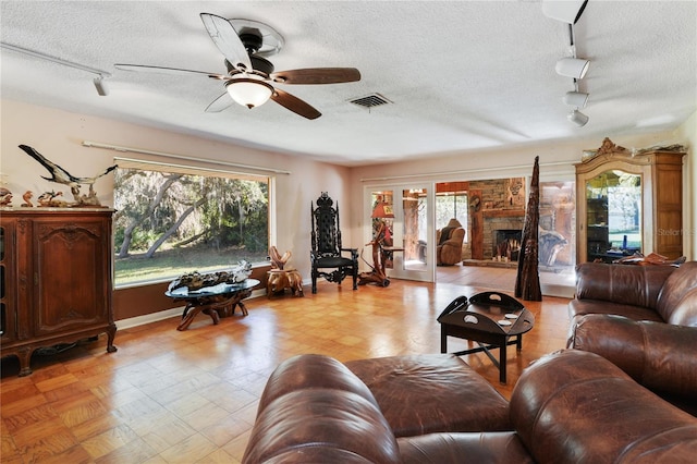 living area with rail lighting, a fireplace, visible vents, and a textured ceiling