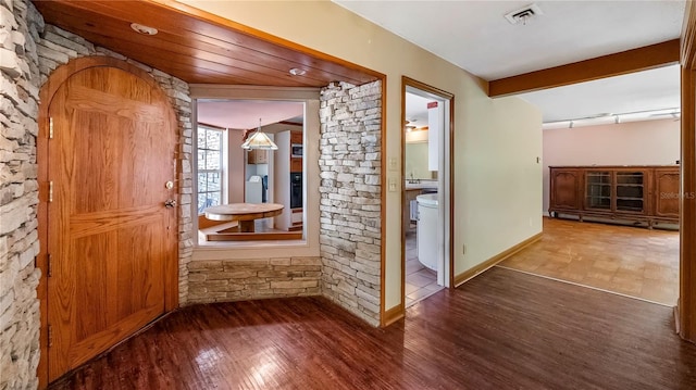 hall with baseboards, visible vents, wood finished floors, beamed ceiling, and track lighting