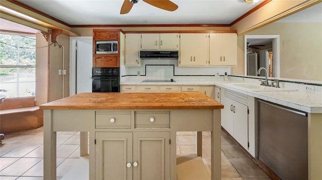 kitchen featuring light tile patterned floors, tasteful backsplash, extractor fan, black appliances, and a sink