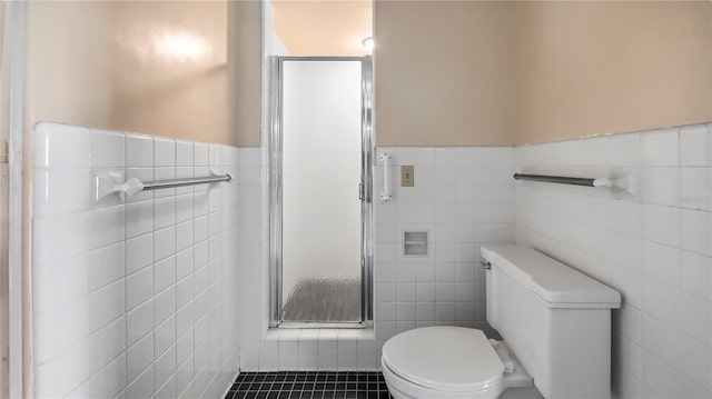 full bathroom with tile patterned flooring, toilet, tile walls, wainscoting, and a shower stall