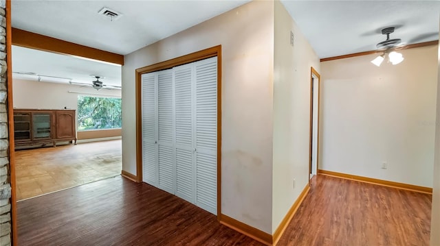 hallway featuring visible vents, baseboards, and wood finished floors