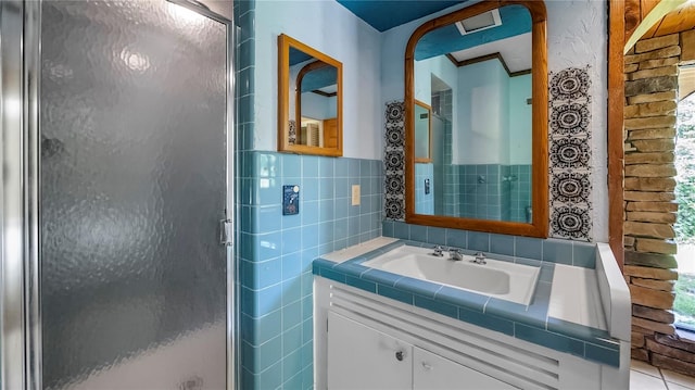 bathroom with a stall shower, a wainscoted wall, tile walls, and vanity