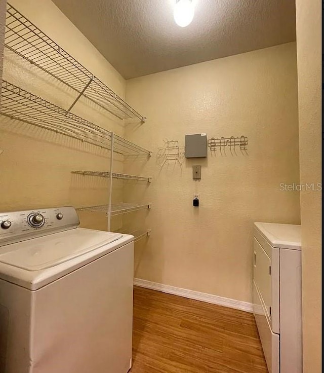 laundry room with wood-type flooring, washing machine and clothes dryer, and a textured ceiling